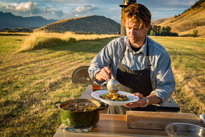 Dishing up the Garden Bounty Beef Stew with Hay-Roasted Onions outside on the Lockhart Ranch