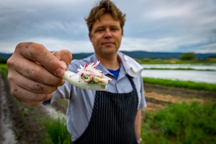 Eric Wilson holding a up an edible Chinese bok choy soup spoon topped with a creamy mixture of smoked trout, freshly grated horseradish and crème fraiche. Julienned matchsticks of radish add a pop of color on top.