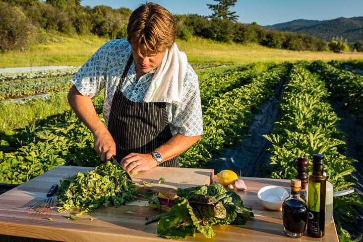 Chef Eric Wilson roughly chopping a huge pile of greens before braising them down