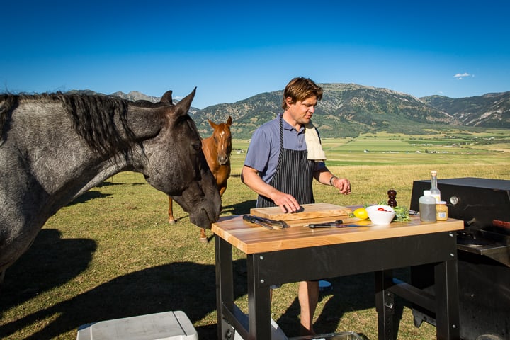 A few curious horses surround Eric as he prepares to start cooking outside on the Robinson Family Farm & Ranch 