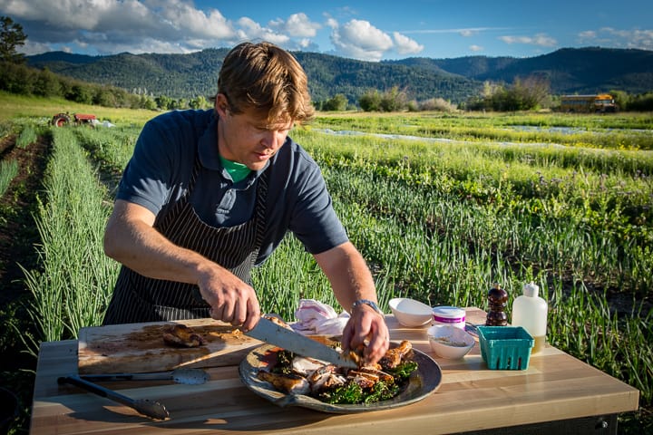 Chef Eric Wilson plating the Cast Iron Spatchcocked Chicken with Crispy Grilled Kale on location in the field of Teton Full Circle farm