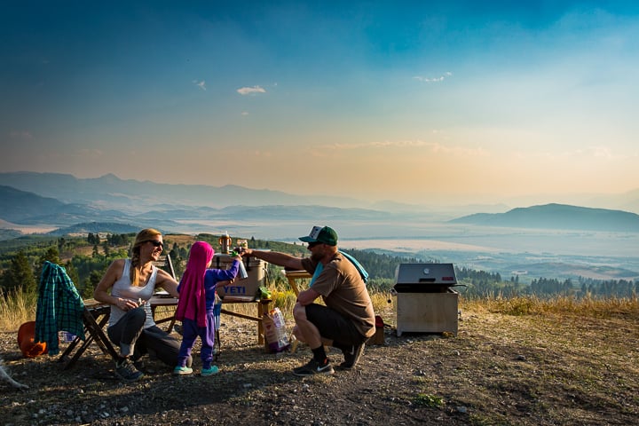 Arden Oksanen camping with the fam toasting in front of a beautiful valley backdrop