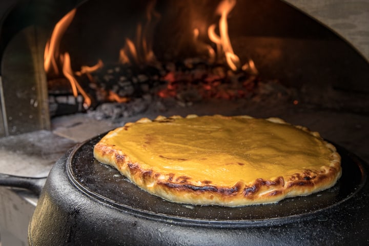 Cooking Wood Fired Pumpkin Crostata on an upside down cast iron pan in and wood fired oven