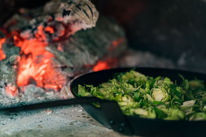 Steel pan sautéing Wood Fired Shaved Brussels Sprouts in a wood fire oven