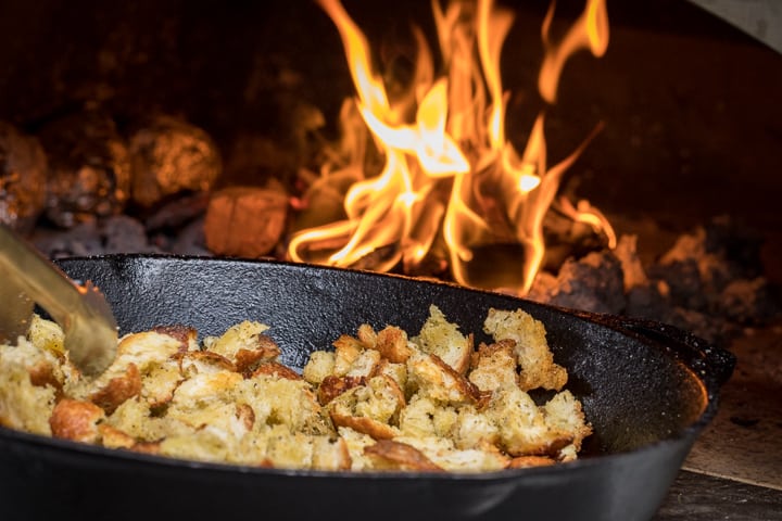 Hand torn pieces of Wood Fired Sourdough Stuffing crisping up in a cast iron and inside a wood oven