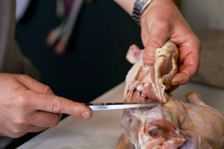 Breaking down a whole chicken. Removing the oyster and bending the leg back to expose the hip joint and remove from the chicken carcass