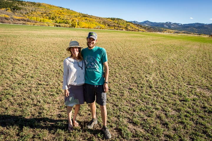 Eirka Eschholz and Ken Michael standing on a wide open field and the new home of their Teton Full Circle Farm. Permanently protected as farmland forever.